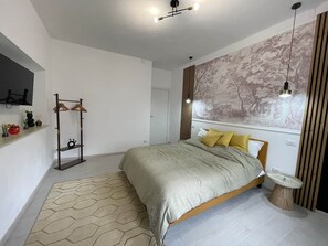 A modern bedroom with a bed, a side table, a wall-mounted shelf, and a geometric-patterned rug.