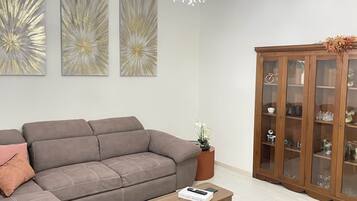 Uma sala de estar moderna com um sofá cinzento, um armário de madeira e arte abstrata na parede.