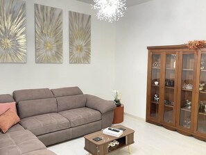 A modern living room with a grey sofa, a wooden cabinet, and abstract wall art.