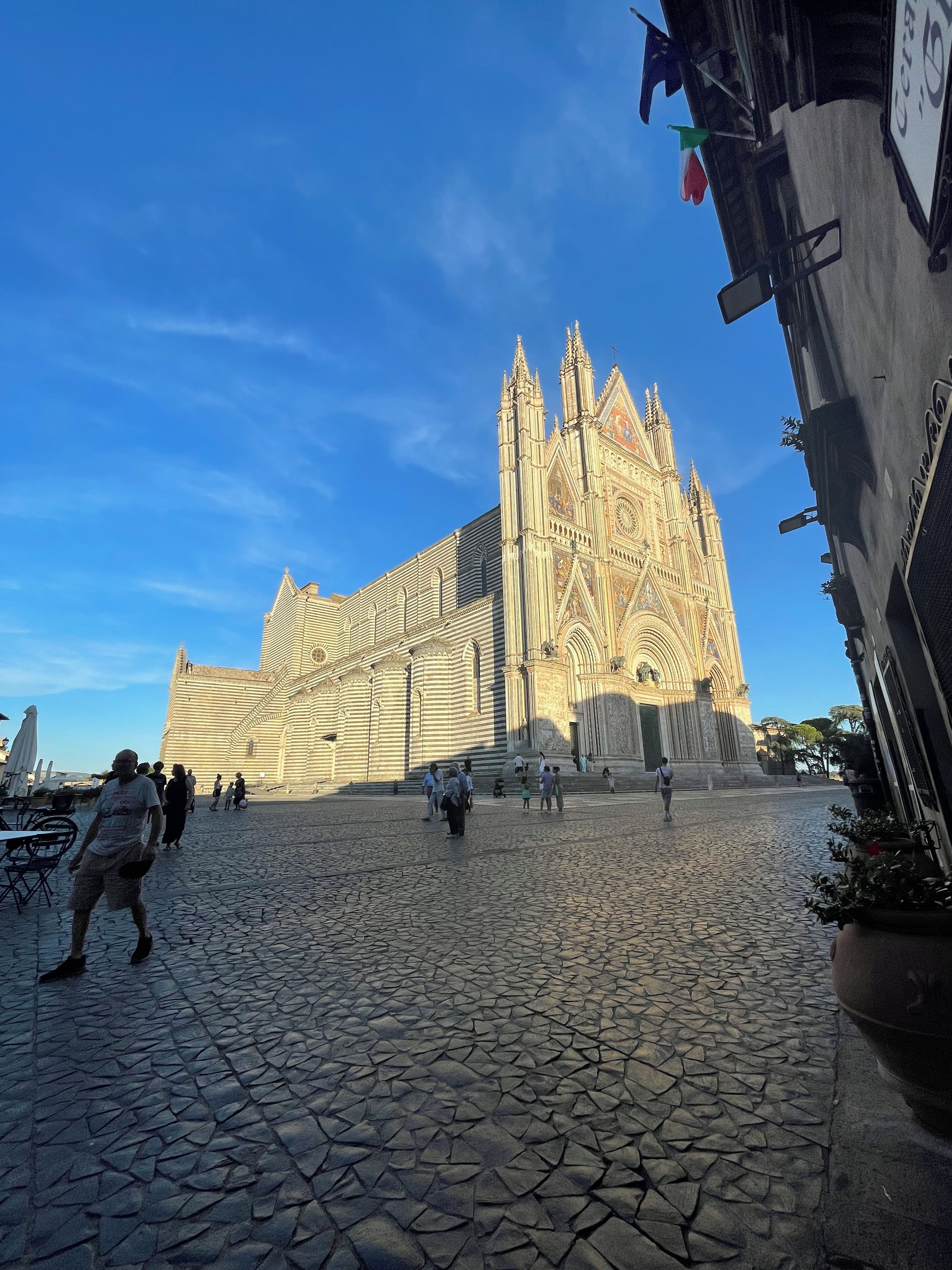 Une cathédrale historique à l’architecture complexe, une place pavée et quelques personnes qui se promènent.