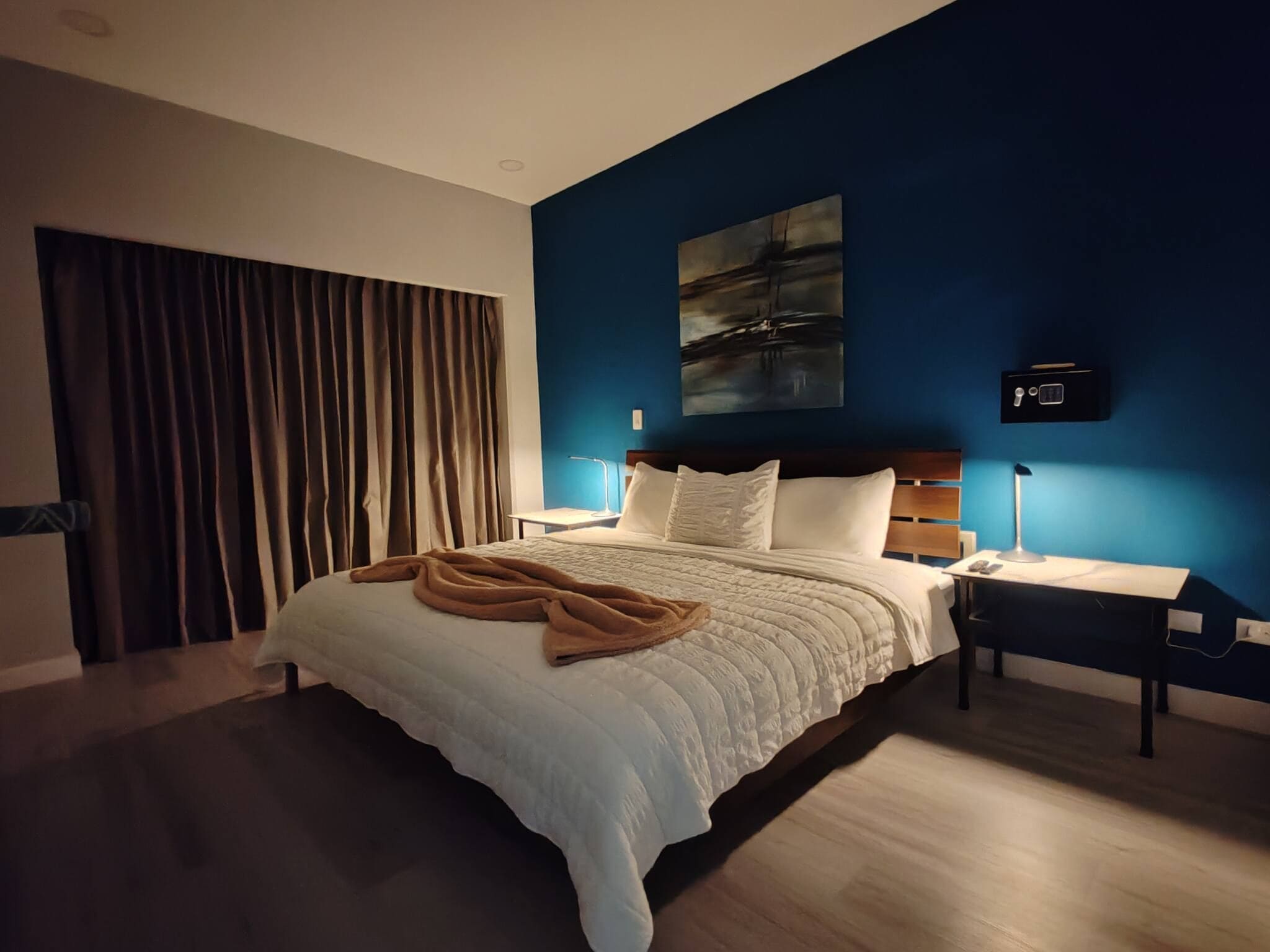 Ein modernes Hotelzimmer mit einem großen Bett, einem Schreibtisch und einem Nachttisch.