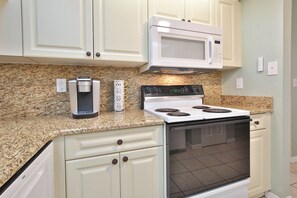 A kitchen with white cabinets, a built-in microwave, a stovetop with four burners, a coffee maker, and a thermostat. - 15 Min from AMI Beaches, Pickleball, Basketball. Free WIFI (Bradenton)