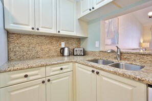 A kitchen with granite countertops, a stainless steel sink, and white cabinetry. - 15 Min from AMI Beaches, Pickleball, Basketball. Free WIFI (Bradenton)