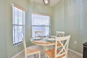 A dining area with a round table, four chairs, and two windows with blinds. - 15 Min from AMI Beaches, Pickleball, Basketball. Free WIFI (Bradenton)