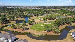 A golf course with multiple ponds, surrounded by trees and residential buildings in the background. - Golf Resort Condo, Pool, Near Broadway Beach (Myrtle Beach)