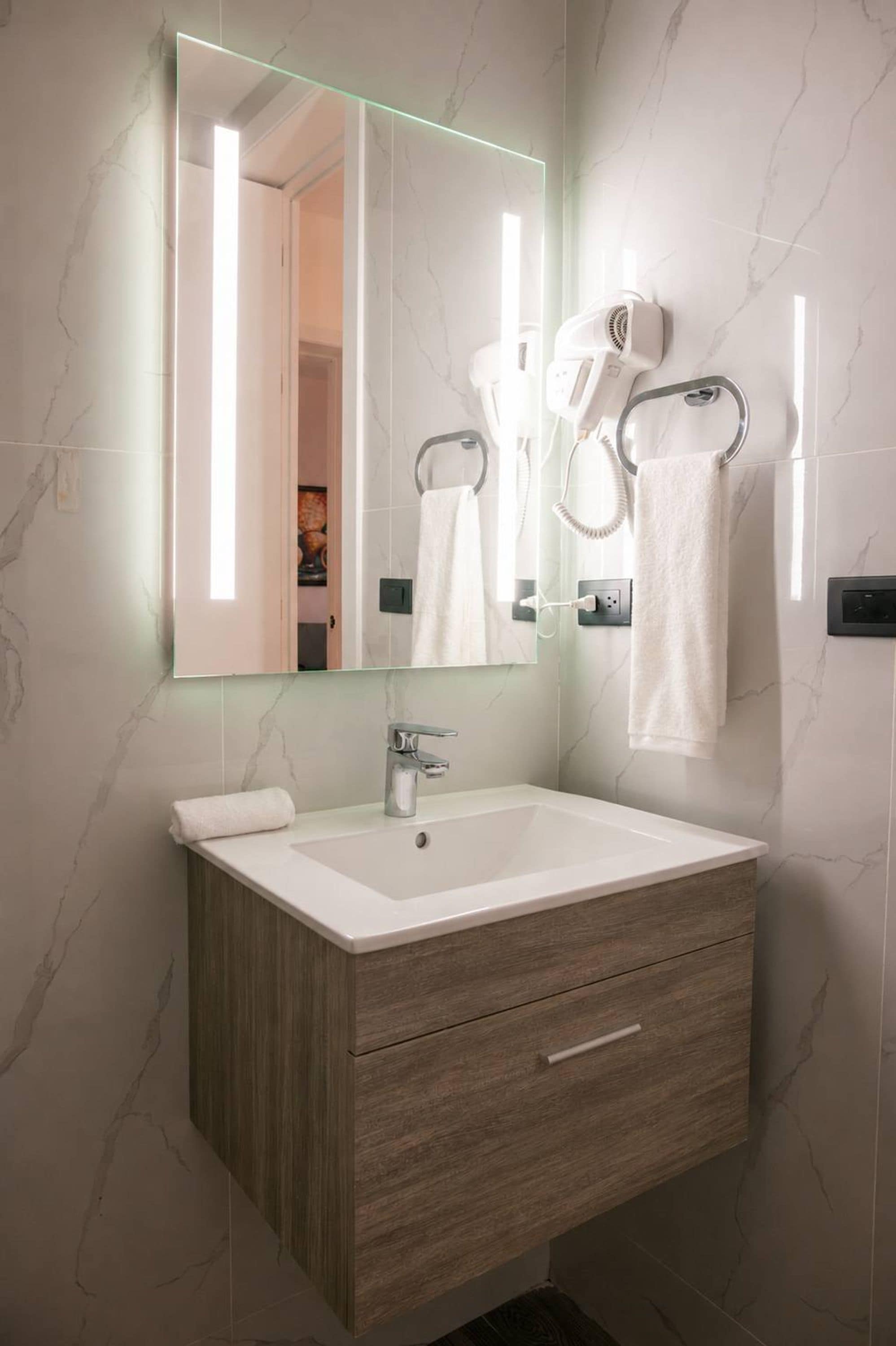 A modern bathroom with a large mirror, a sink, and a towel rack.
