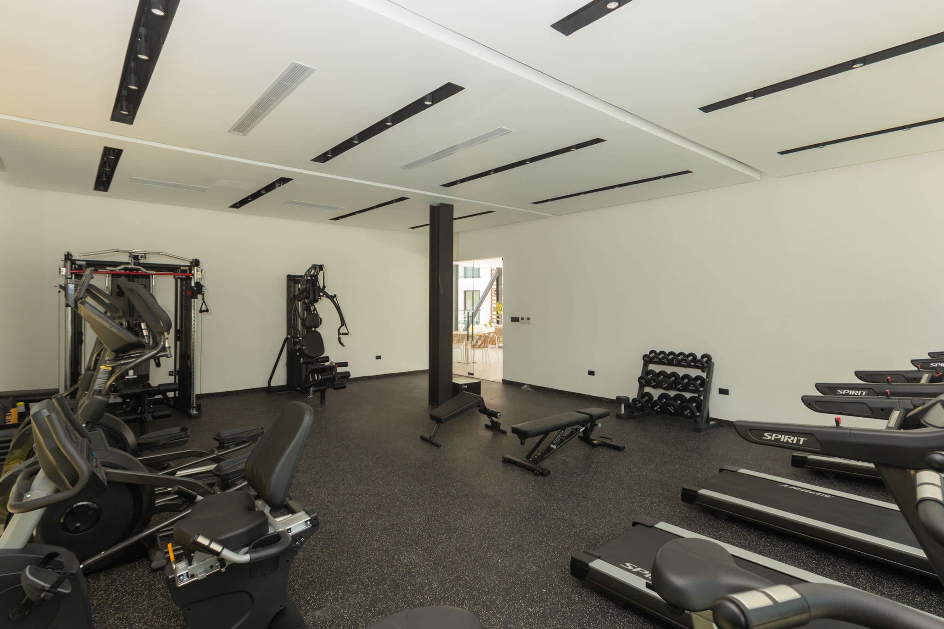 A gym with various exercise equipment including treadmills, weight machines, and free weights.