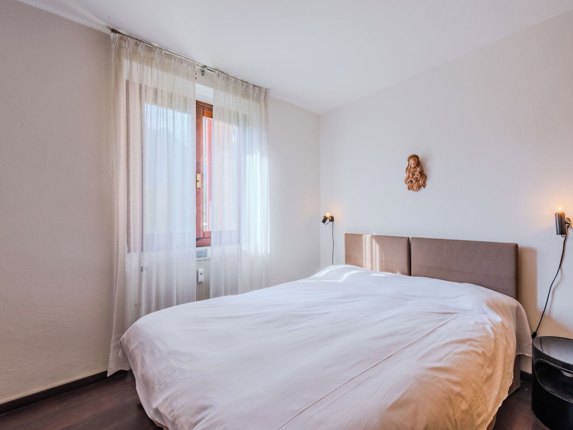 Ein Hotelzimmer mit einem Bett, einem Nachttisch, einer Lampe und einer Wandleuchte.