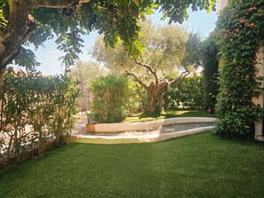 Ein gepflegter Garten mit verschiedenen Pflanzen und einem kleinen Wasserspiel.