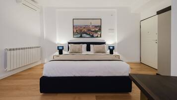 A modern bedroom with a large bed, a cityscape painting, and a wardrobe.
