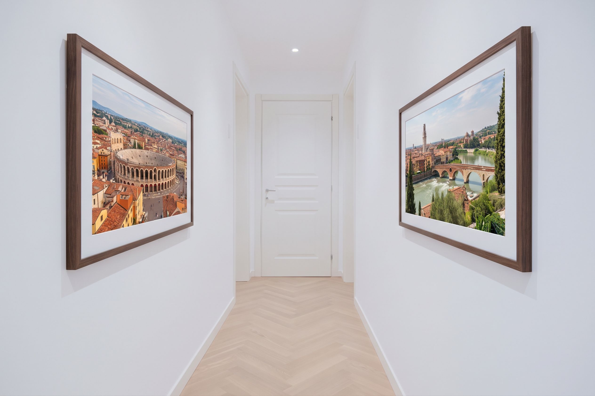 A hallway with two framed photographs on the walls, a white door, and a wooden floor.