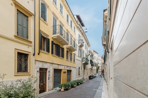 A narrow street with buildings on both sides, featuring balconies and shutters. - ApartmentsArena - Residenza Cantore (Verona)