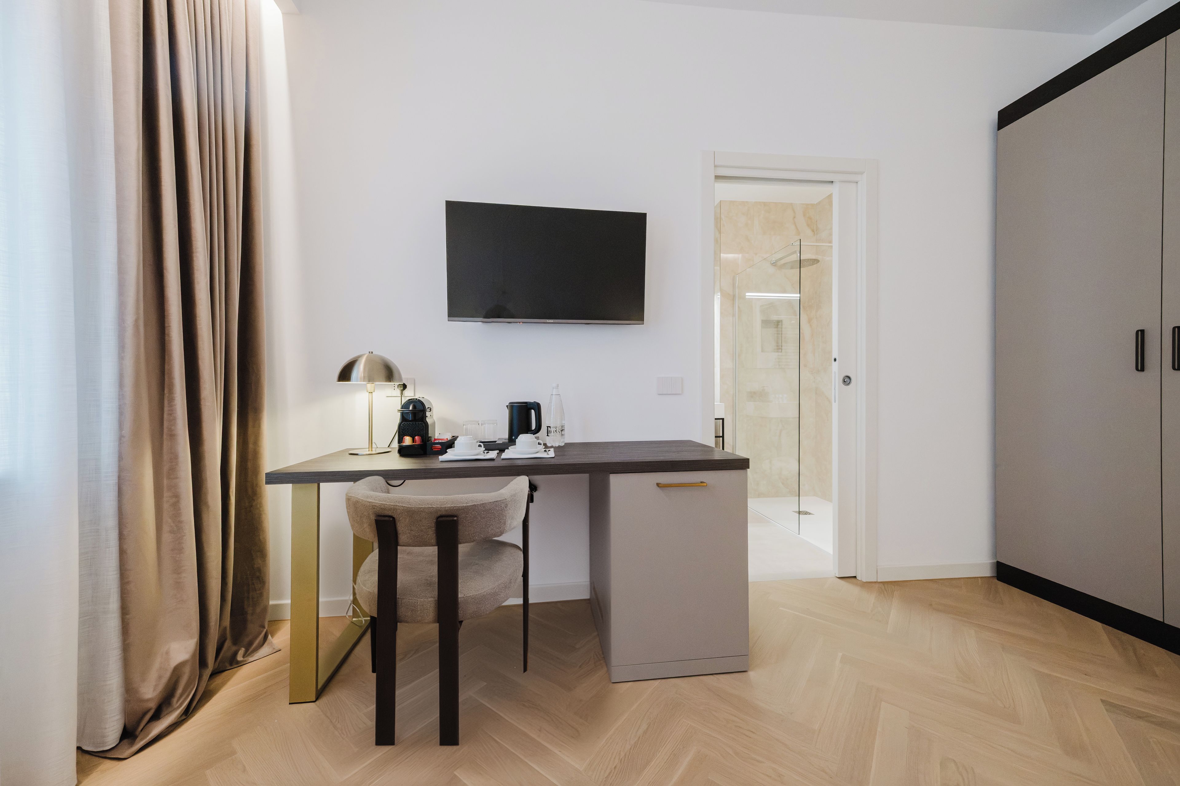 A compact living space with a desk, chair, and a television mounted on the wall.