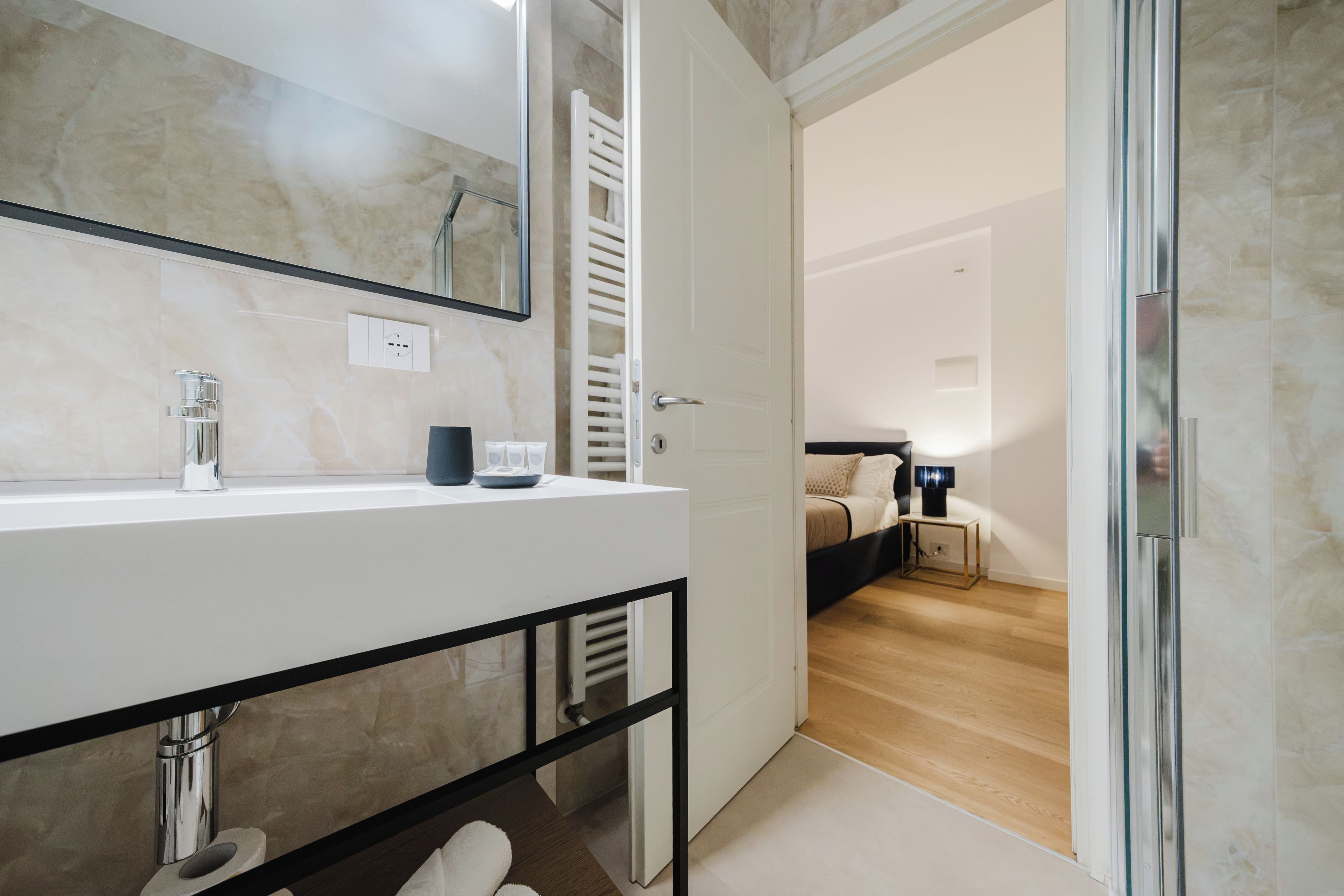 A modern bathroom with a white vanity, a mirror, and a towel rack.