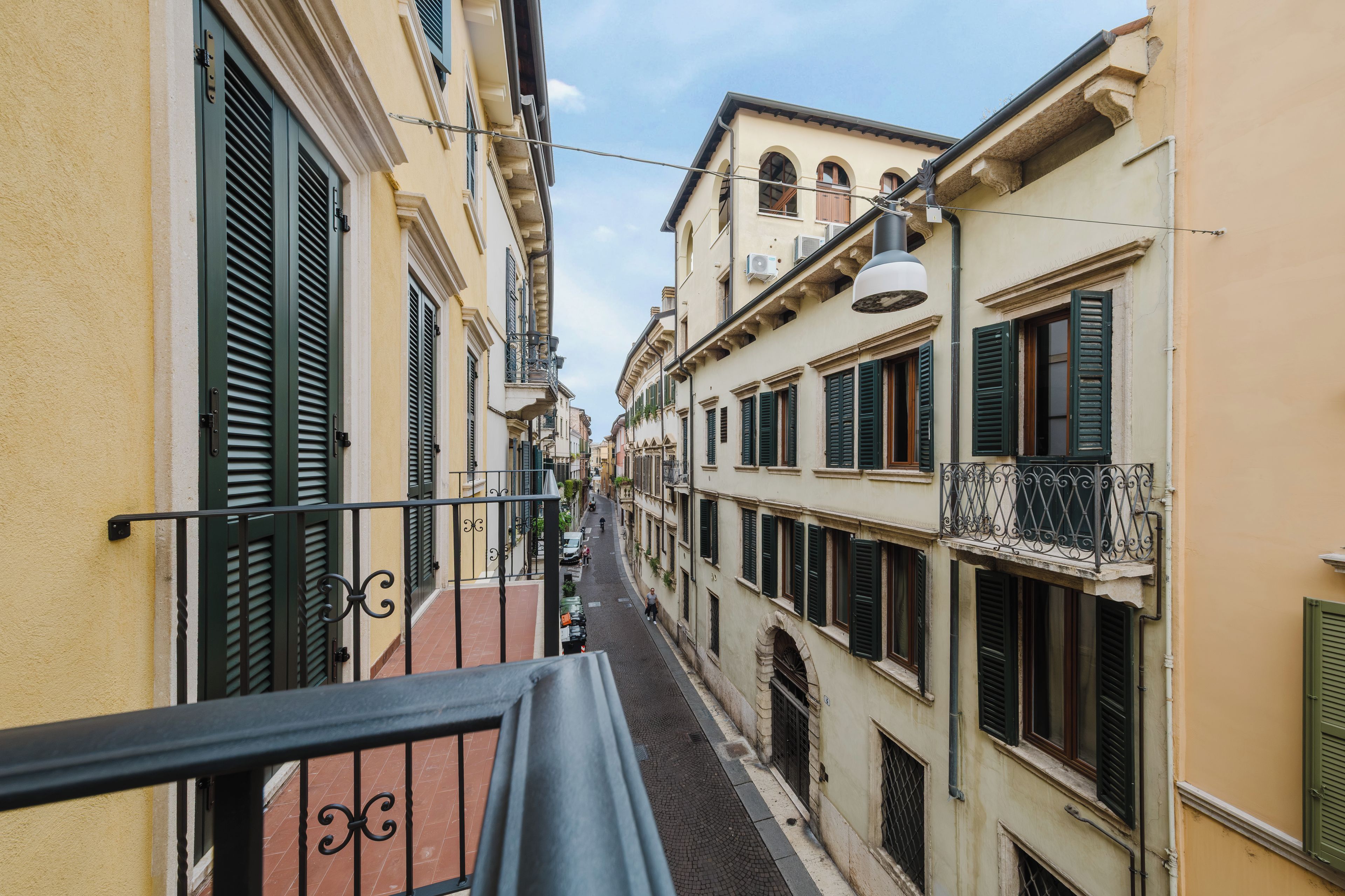 Eine schmale Gasse, gesäumt von Gebäuden mit Balkonen und Fensterläden.
