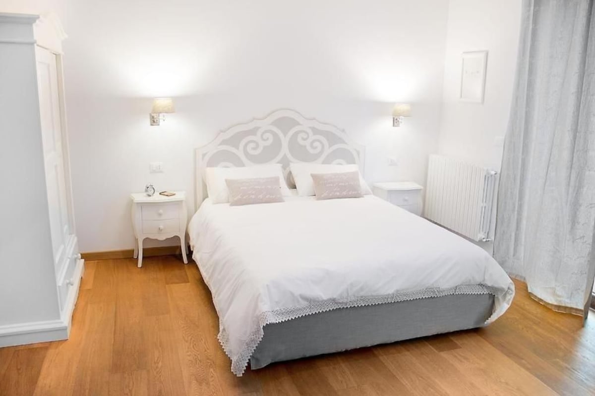 Un dormitorio con cama, mesitas de noche y un radiador.