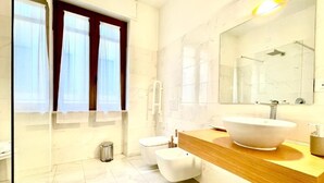 Une salle de bain moderne avec un grand miroir, un lavabo blanc et des toilettes.