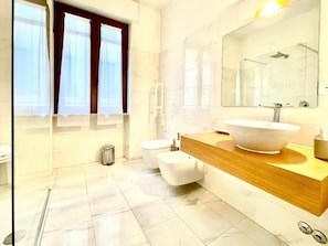 Un baño moderno con un espejo grande, un lavamanos blanco y un inodoro.