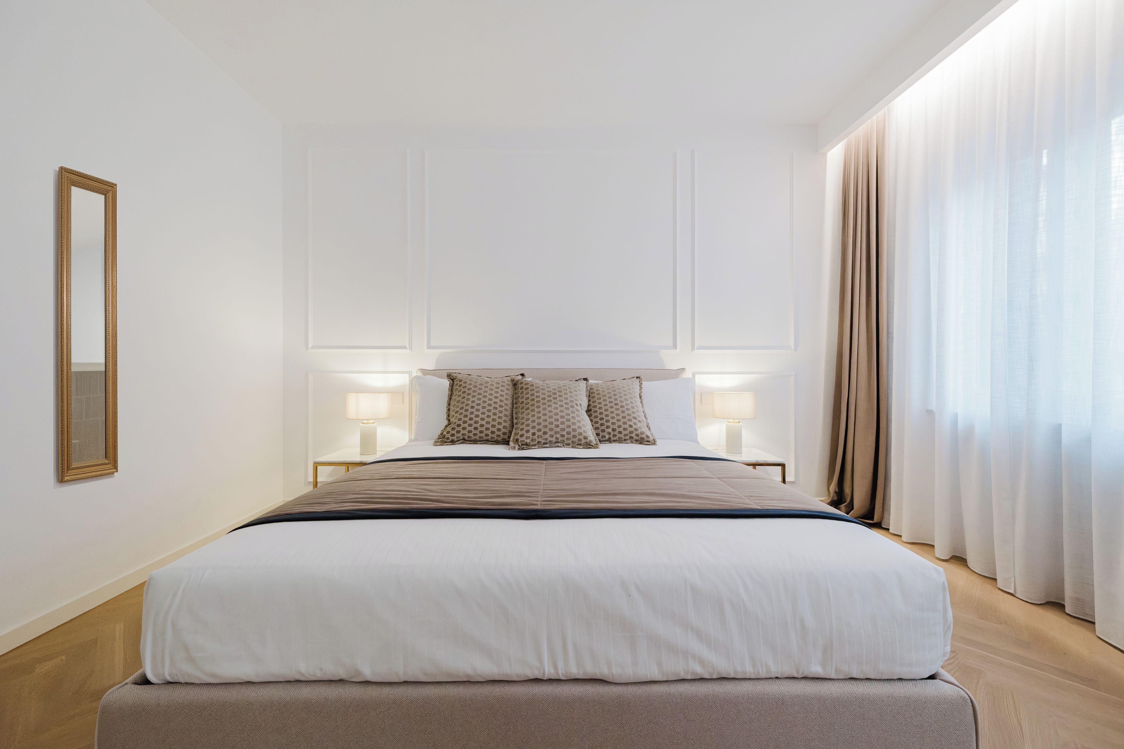 Ein Hotelzimmer mit einem großen Bett, Nachttischlampen und einem Spiegel an der Wand.