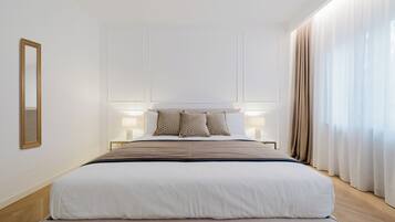 Ein Hotelzimmer mit einem großen Bett, Nachttischlampen und einem Spiegel an der Wand.