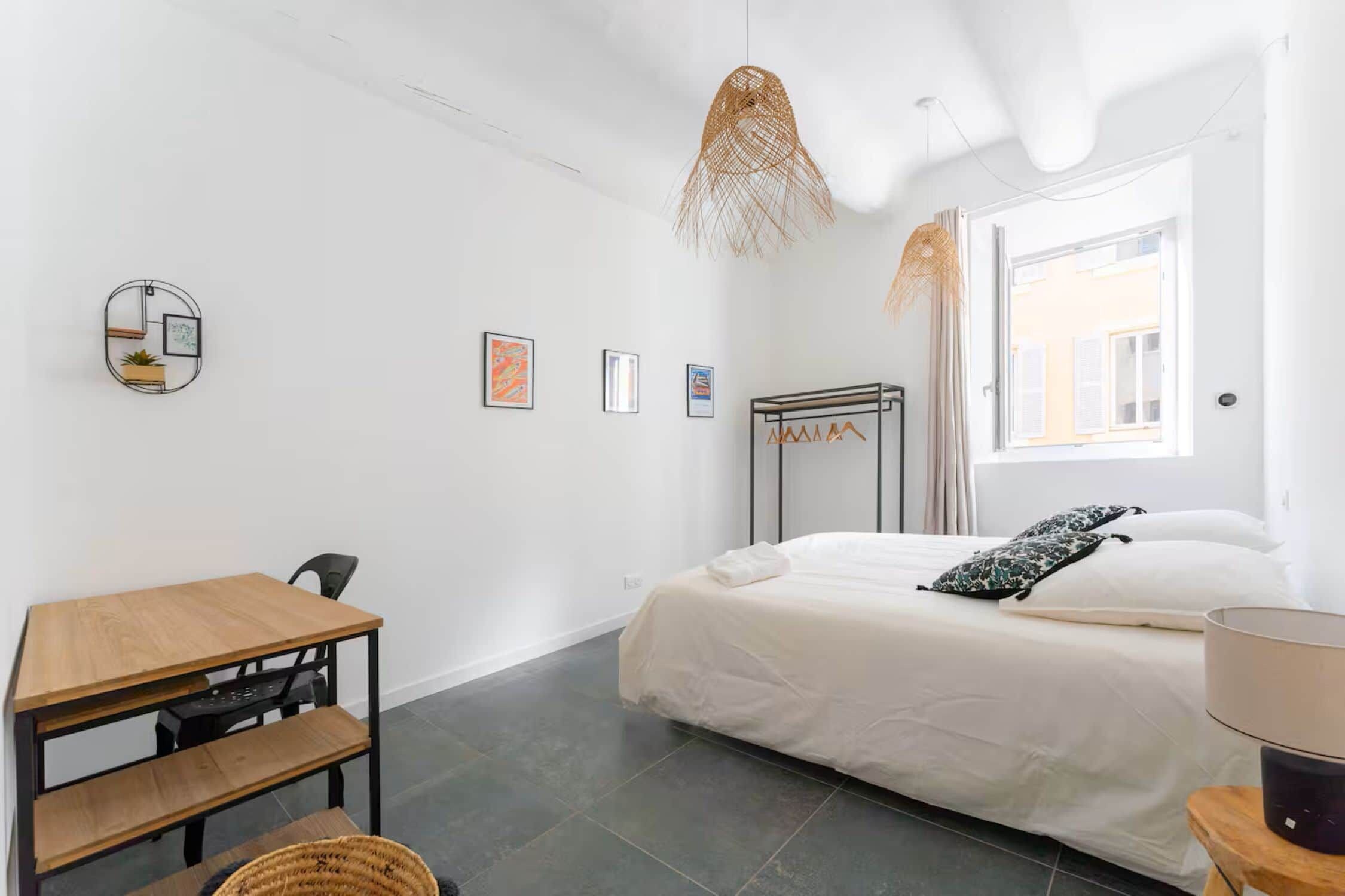 Una camera da letto minimalista con un letto, una scrivania e una lampada a sospensione.