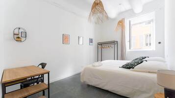 Una camera da letto minimalista con un letto, una scrivania e una lampada a sospensione.