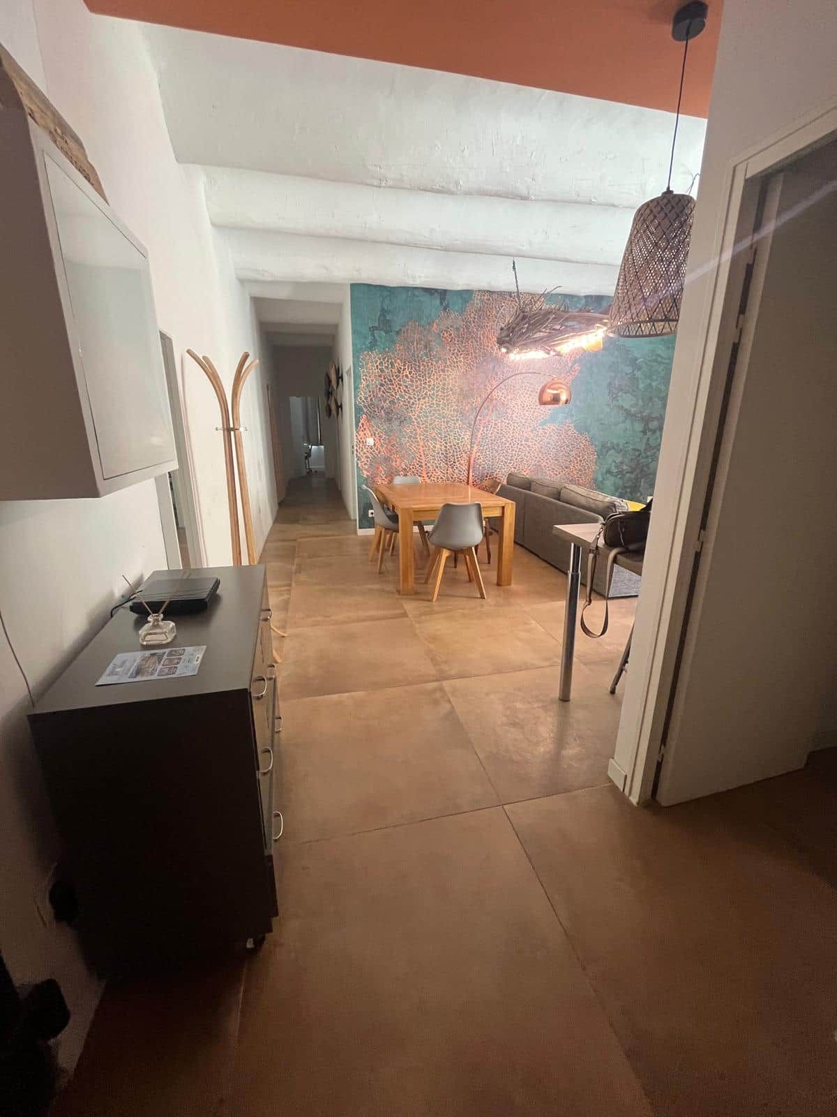 Un interior moderno con comedor, sofá y una pared decorada con un mural de un árbol.