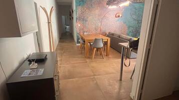 Un interior moderno con comedor, sofá y una pared decorada con un mural de un árbol.