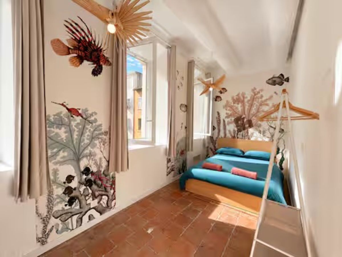 Une chambre à coucher avec un lit, une fresque murale et une fenêtre.