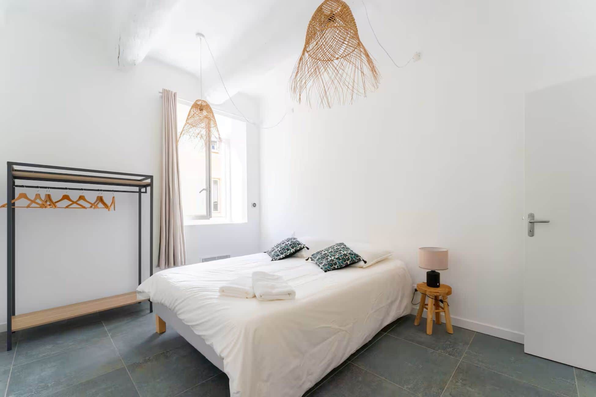 Un dormitorio con cama, lámpara colgante, armario y mesita de noche.
