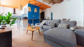 Un soggiorno moderno con un divano grigio, un tavolino in legno e lampade a sospensione.