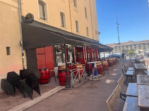 Area esterna con tavoli e sedie, una botte rossa e un cartello per un pub irlandese.