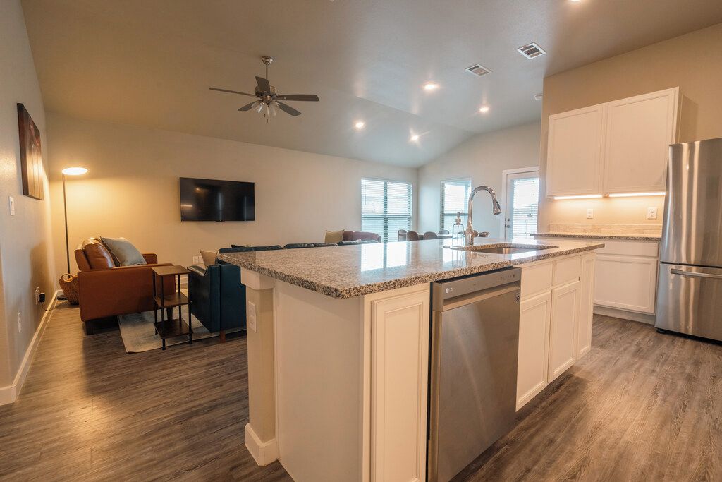 A modern kitchen with a central island, built-in appliances, and a ceiling fan.