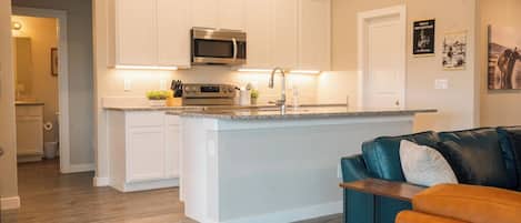 Una cocina moderna con armarios blancos, un microondas integrado y una encimera de granito.