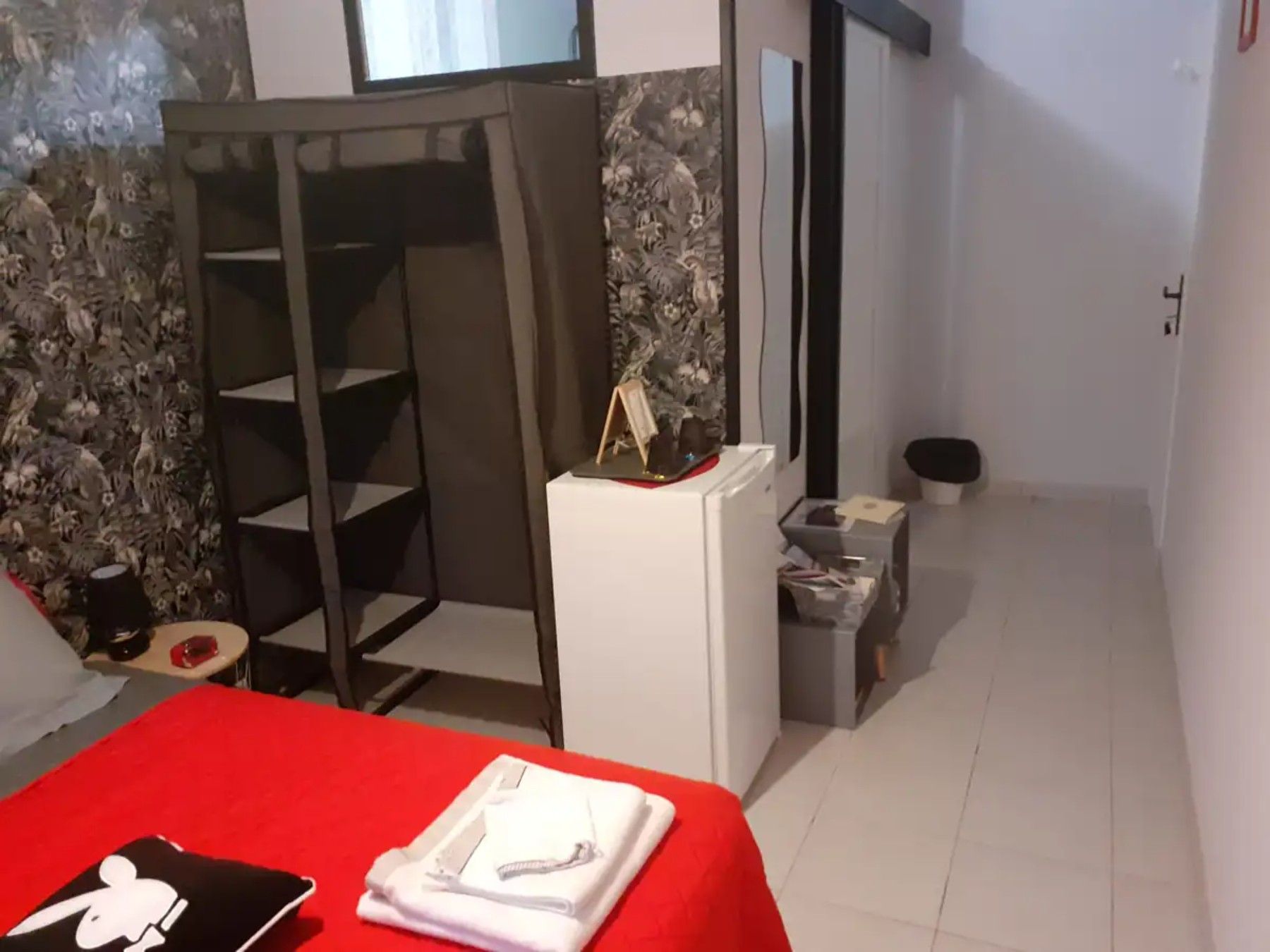 A room with a bed, a small desk, a chair, a wardrobe, and a mirror.