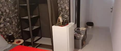 A room with a bed, a small desk, a chair, a wardrobe, and a mirror.