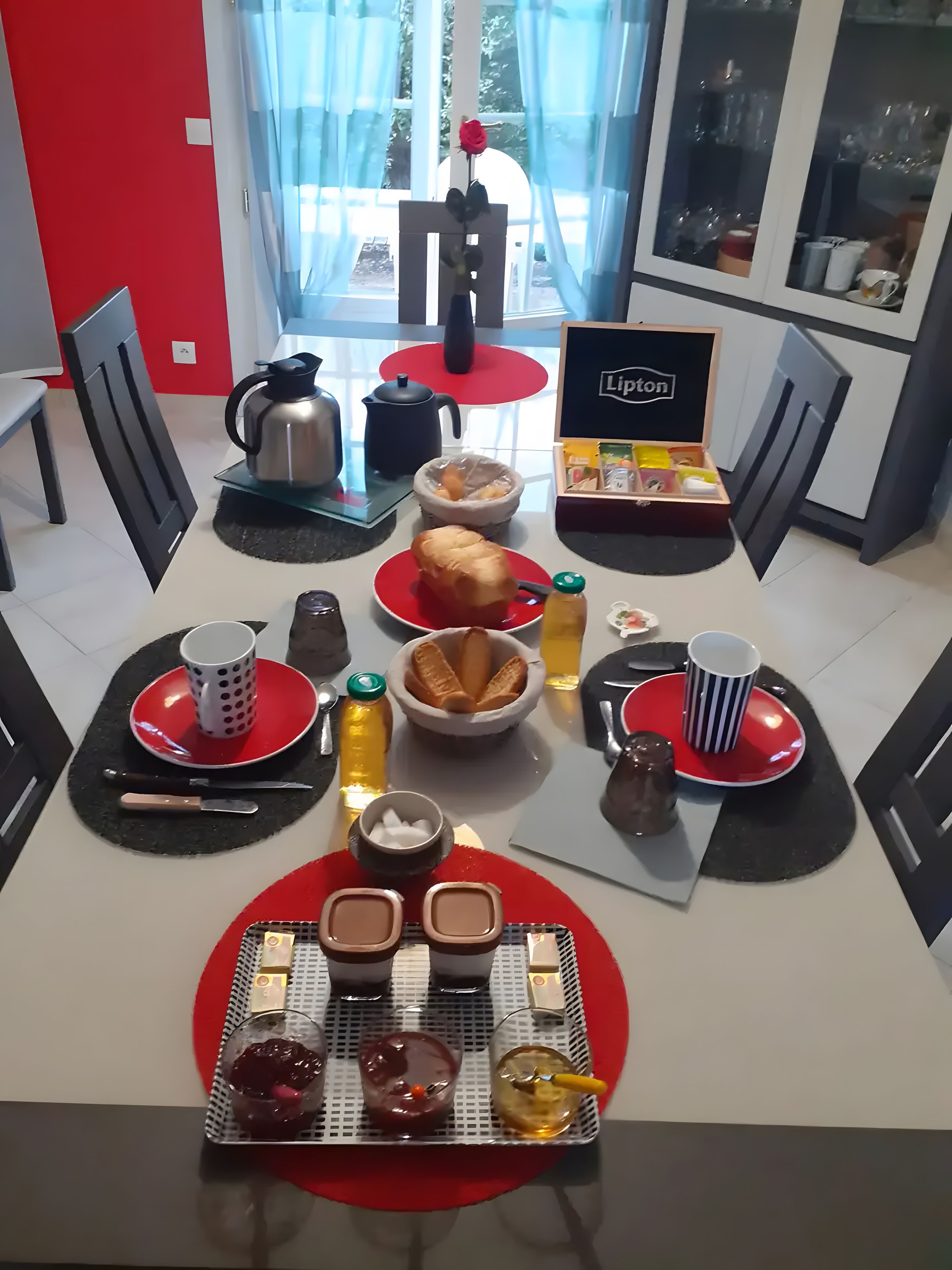 Un coin repas avec une table dressée pour deux personnes, où l’on trouve une variété de plats et de boissons.