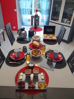 A dining area with a table set for two, featuring a variety of food items and drinks.