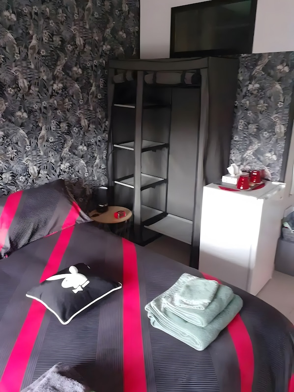 A bedroom with a bed, a wardrobe, a bedside table, and a television.