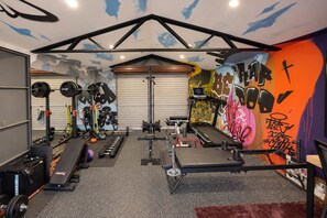 A gym with weightlifting equipment, treadmills, and a wall with graffiti. - Stylish Family Retreat with Sauna, Gym, Basketball & Alfresco (Saint Clair)