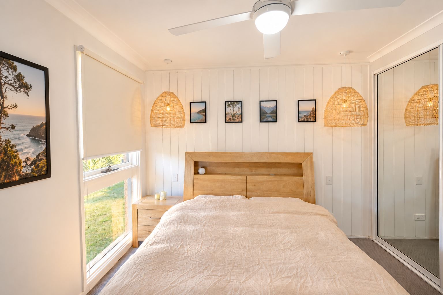 A bedroom with a large bed, a ceiling fan, and a view of the outdoors.