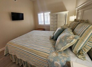 A bedroom with a bed, a television mounted on the wall, a window with blinds, and a dresser. - Premium Peaceful Intracoastal Retreat | 2BR • 2BA • Sleeps 6 (Indian Shores)