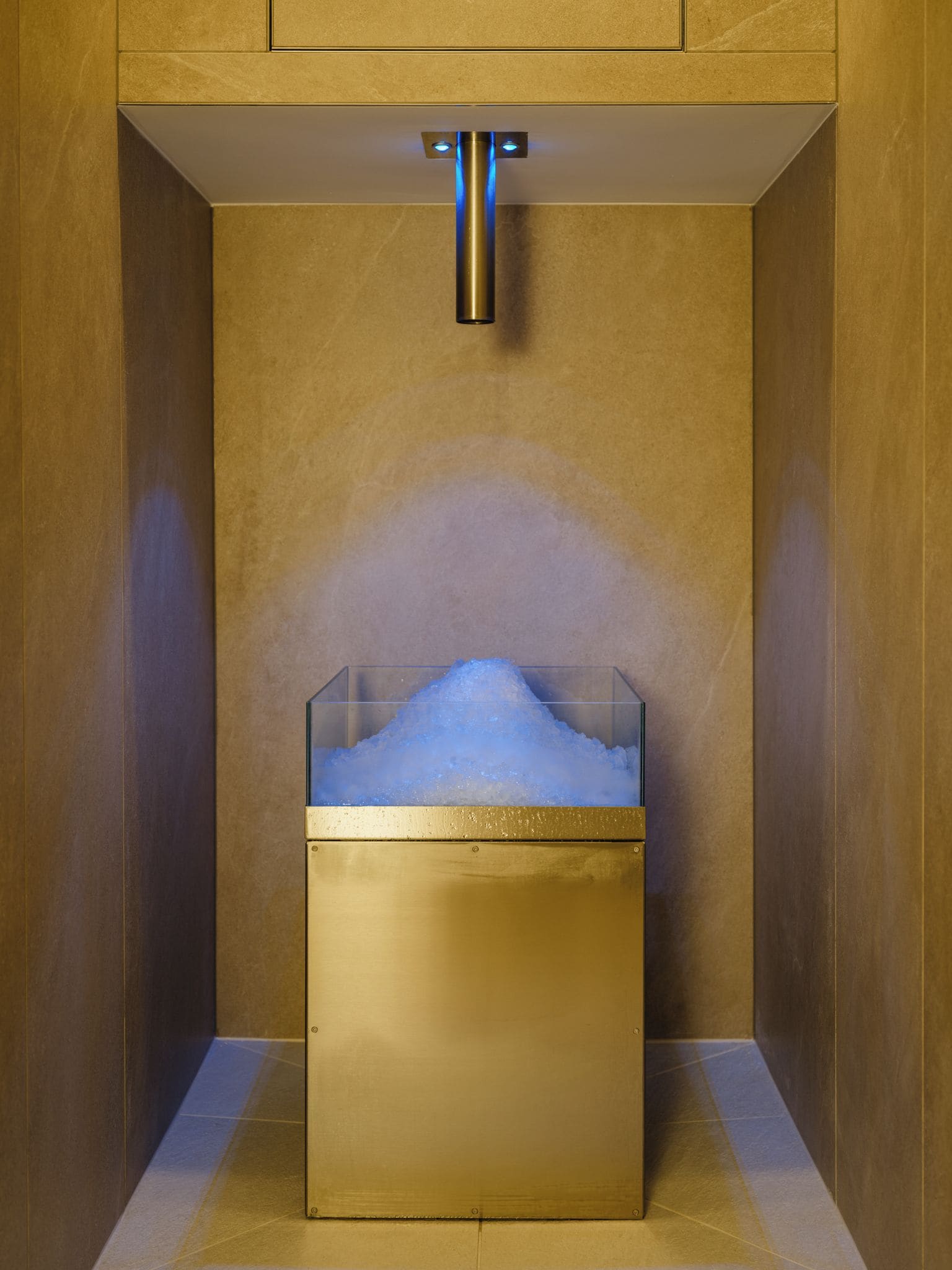 A modern bathroom with a glass container filled with water and a light fixture above it.