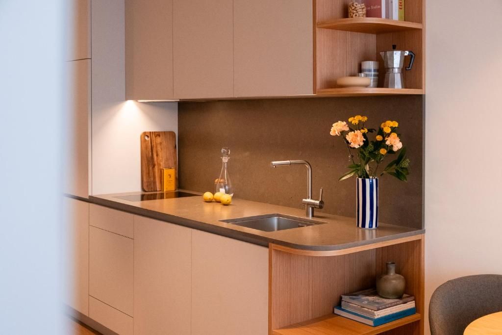 A modern kitchen with a built-in sink, a wooden cutting board, and a vase with flowers.