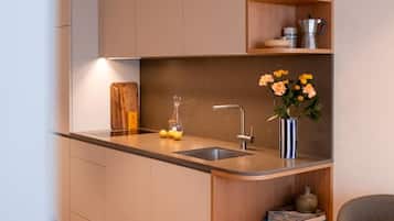 A modern kitchen with a built-in sink, a wooden cutting board, and a vase with flowers.