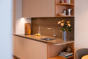Una cocina moderna con un lavamanos integrado, una tabla de cortar de madera y un florero con flores.