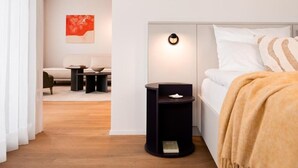 A modern bedroom with a bed, bedside tables, a nightstand, a wall-mounted light, and a painting on the wall. - THE FLAG Lugano Self Check-in (Massagno)