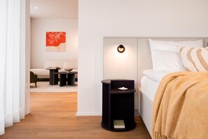Ein modernes Schlafzimmer mit Bett, Nachttischen, einer Wandleuchte und einem Bild an der Wand.