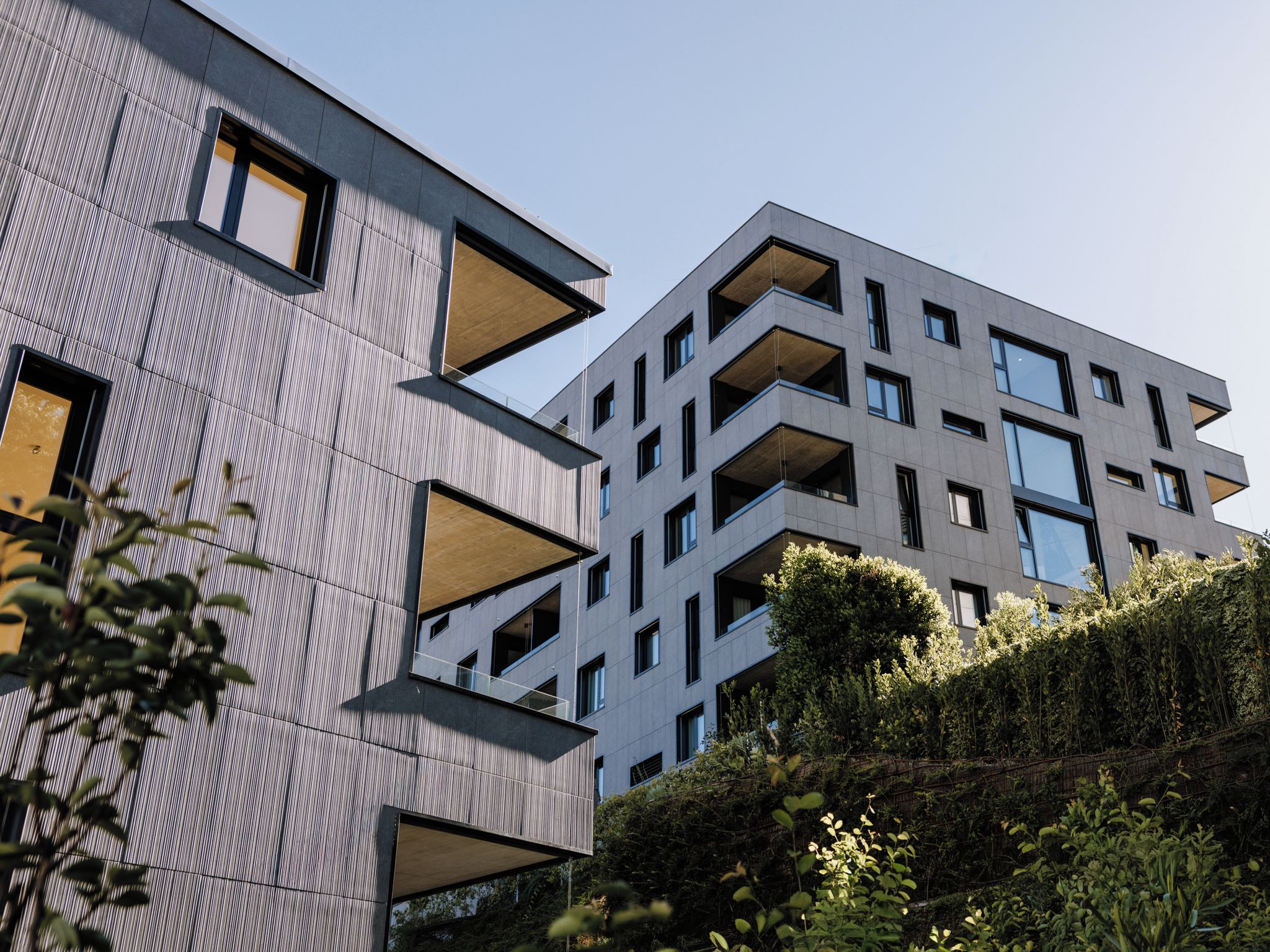 En modern byggnad med en unik arkitektonisk design, utrustad med flera balkonger och stora fönster.