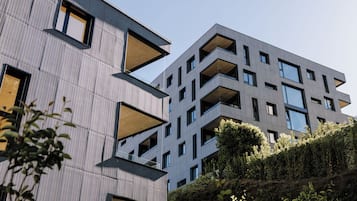 Un edificio moderno con un diseño arquitectónico único, con varios balcones y ventanas amplias.